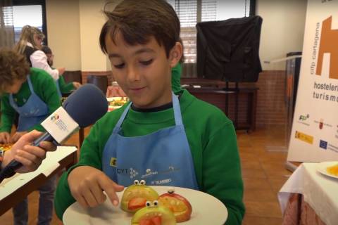 Uno de los escolares mostrando su obra de arte creada con frutas y hortalizas.